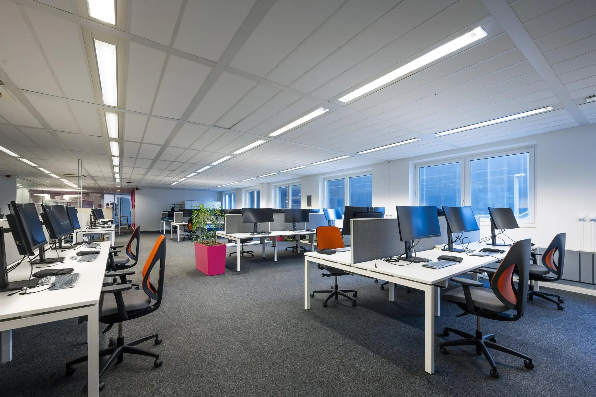 Modern en ruim kantoorpand aan de Johan Cruijff Boulevard met open werkplekken en bureaus met computerschermen.